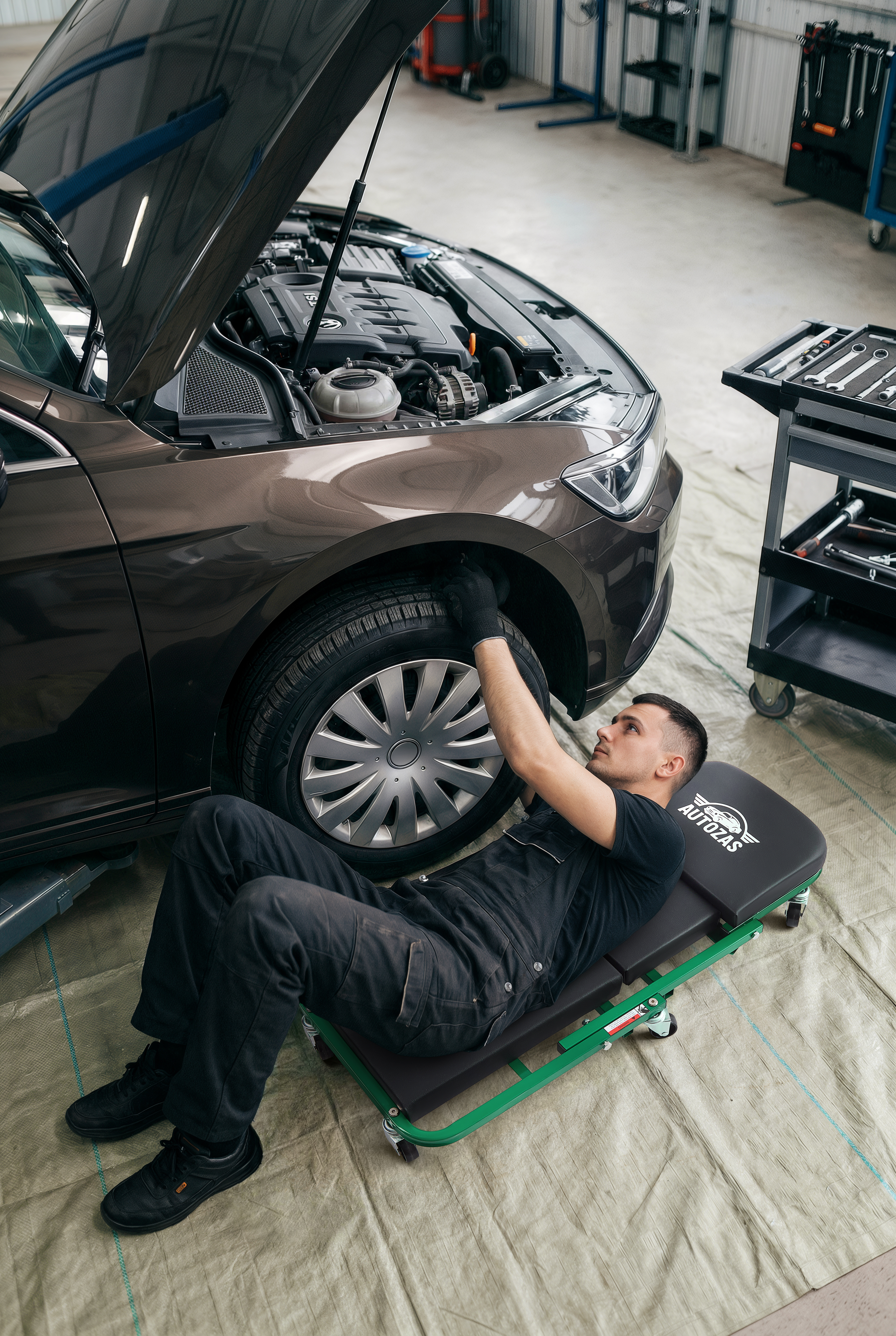Mechanic on Autozas Green shop stool performing driveway wheel and brake service with work light