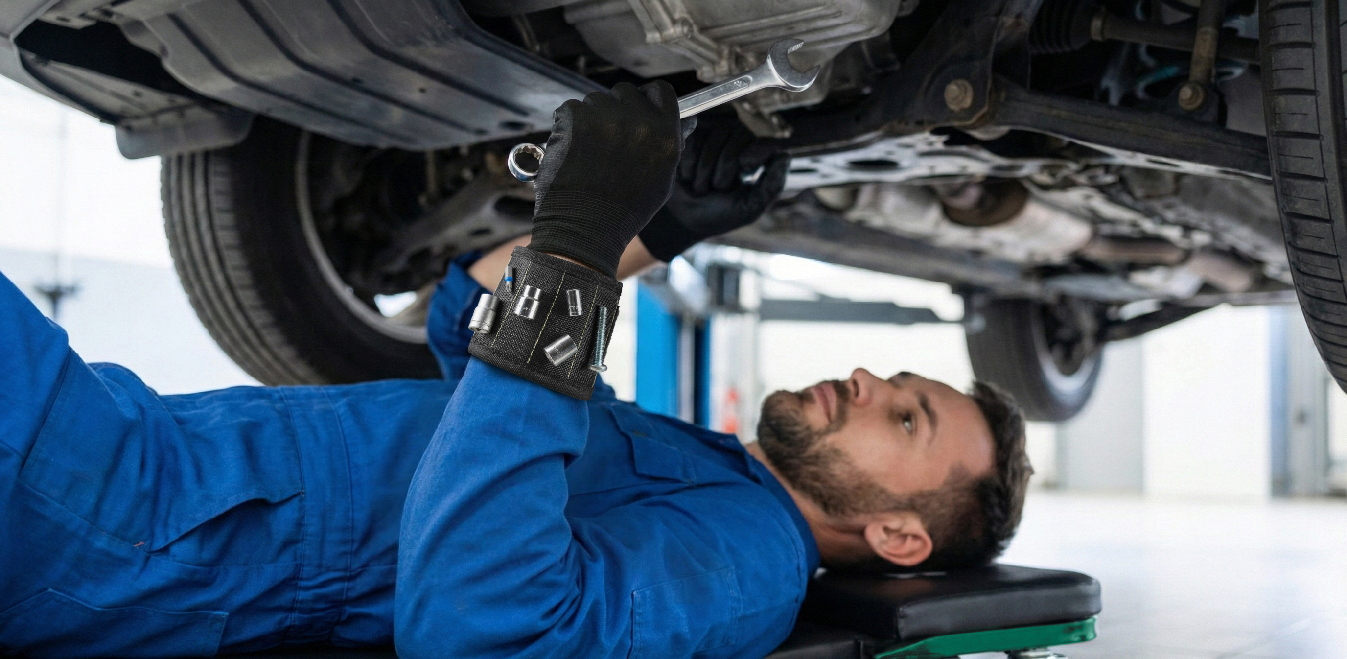 Wide panoramic view: mechanic on Autozas Green creeper performing under-car suspension and brake repair in a home garage